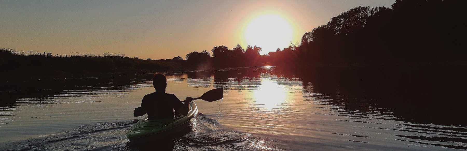 Man kayaking at sunset