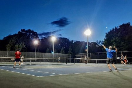 People playing tennis on court at night