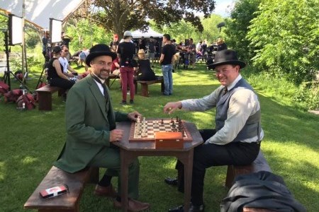Two actors playing chess at a table 