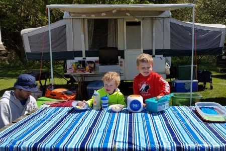 Family at picnic table with camper in the background