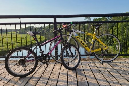 Two bikes leaning up against railing of bridge