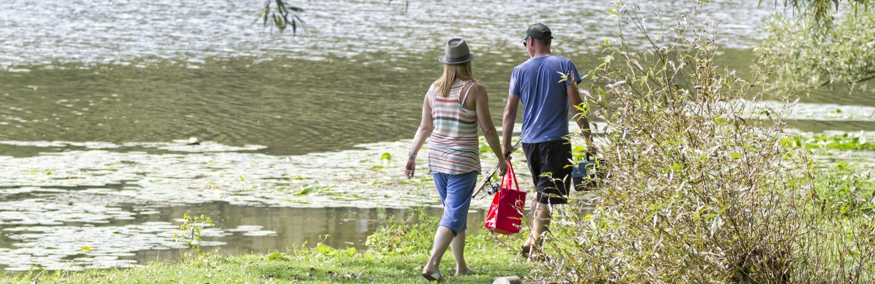 Couple walking along water with fishing poles