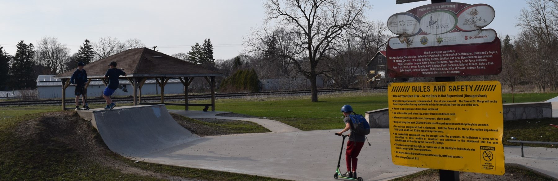 Children on ramps with scooters at skate park