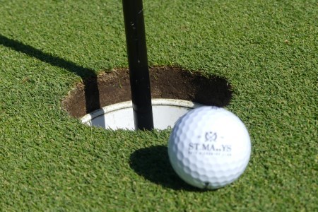 Golf ball on green next to the hole