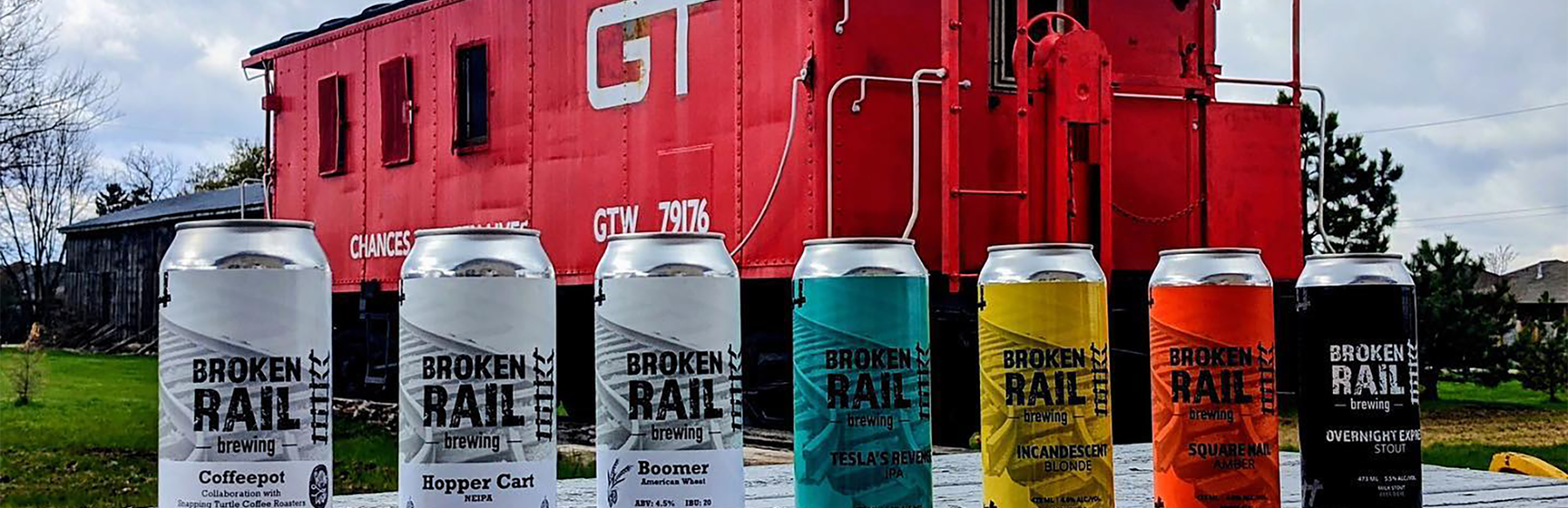 Broken Rail Brewery beer cans in front of a red caboose
